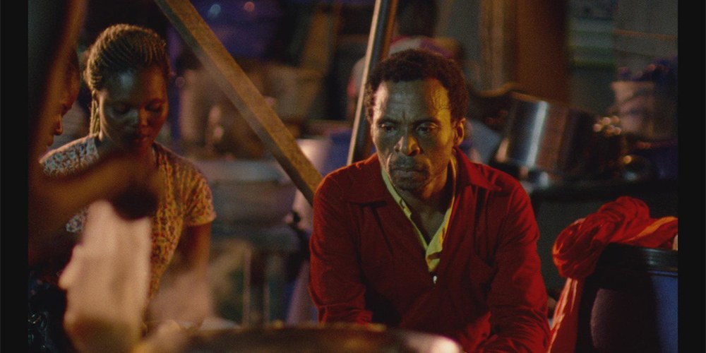 Jude Akwudeki the lead in Eyimofe, a middle aged Nigerian dressed in red overalls sits where he works, and appears sad.