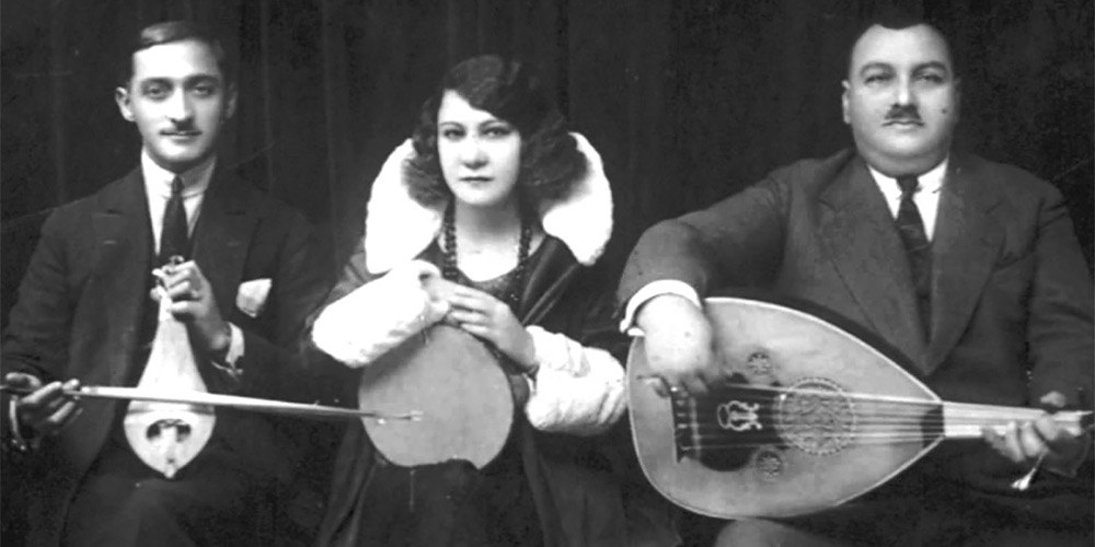 Greek Blues’ singer Roza Eskenazi holding tambourine with two musicians either side