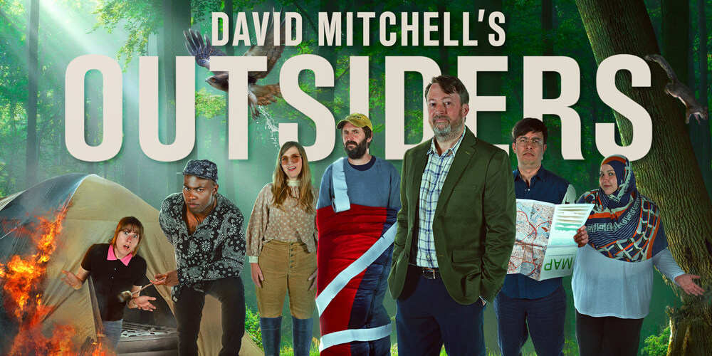 The cast of Outsiders season 2 standing in a forest including David Mitchell, Maisie Adam, Fatiha El-Ghorri, Darren Harriott, Jessica Hynes, Phil Wang and Joe Wilkinson.
