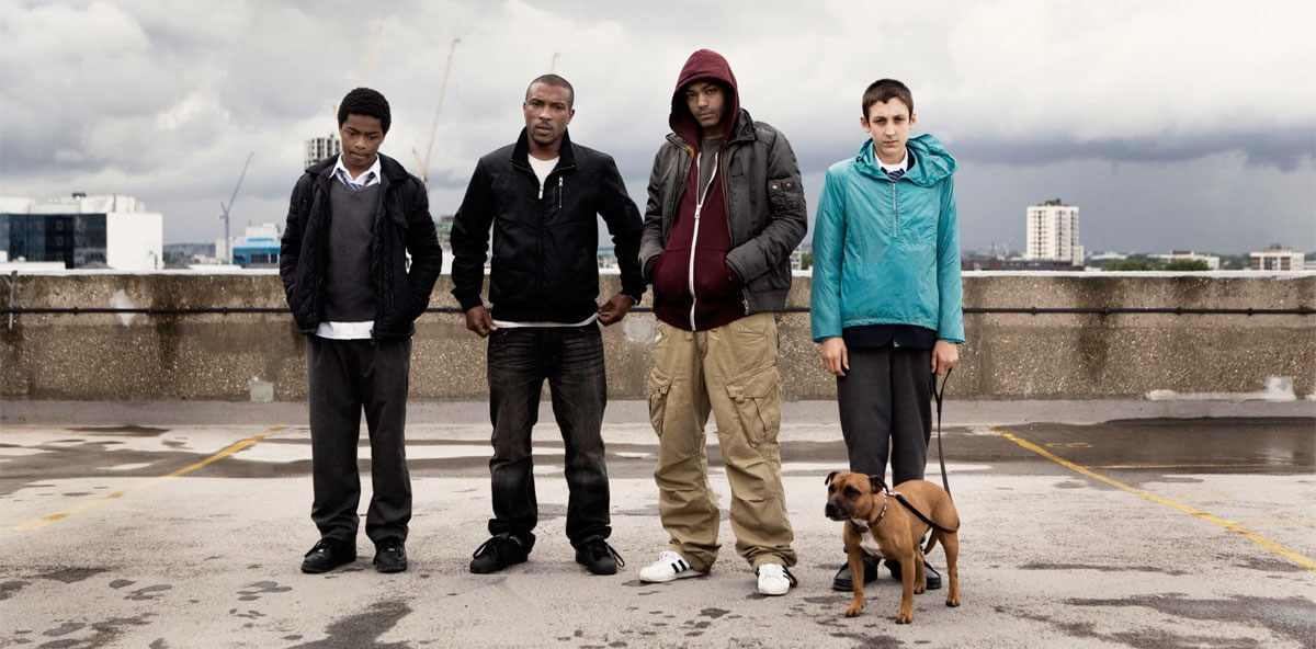 Top Boy: Four Top Boy cast members including Ashley Walters and Kane Robinson on an urban rooftop with a dog